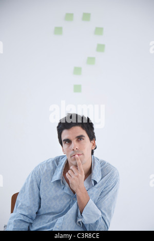 Man thinking with post-it note question makr behind him Stock Photo