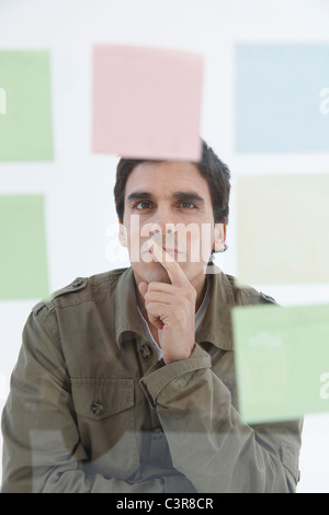 Man looking at different coloured post-it notes Stock Photo
