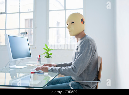 Man in crash test dummy mask in an office Stock Photo