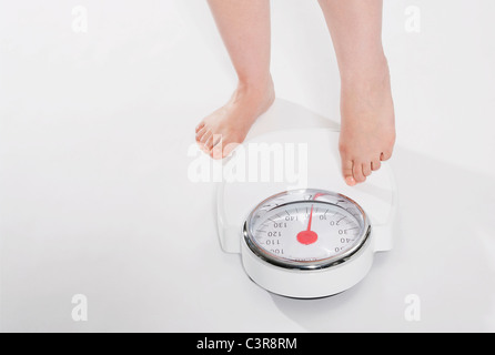 Young woman standing on bathroom scales Stock Photo