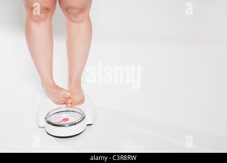 Young woman standing on bathroom scales Stock Photo
