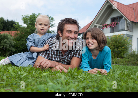Germany, Munich, Father with children in garden, smiling Stock Photo