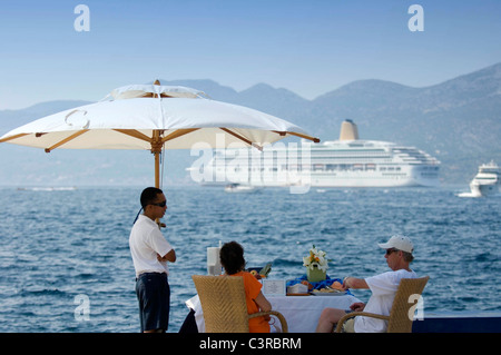 Couple waiting in the shade for a tender to their  cruise ship at the coastal town of  Korčula off the Dalmatian coast. Stock Photo
