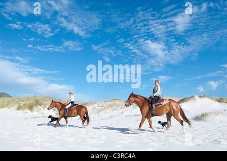 2 people riding horses on the beach Stock Photo