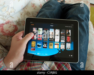 Man browsing digital e-book library on Amazon kindle app on an iPad touch screen tablet computer Stock Photo