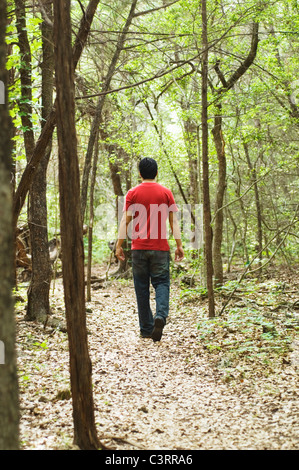 Hispanic man walking on path in woods Stock Photo