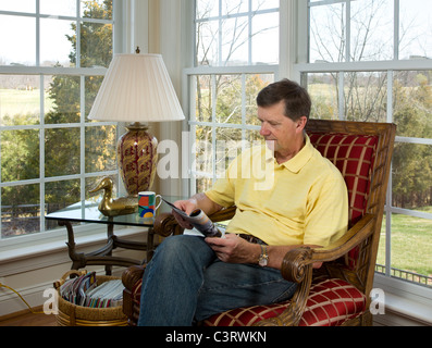 Senior man sitting reading a magazine Stock Photo