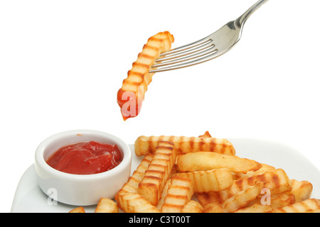 Crinkle cut potato chips and tomato ketchup with a chip dipped in ketchup on a fork Stock Photo