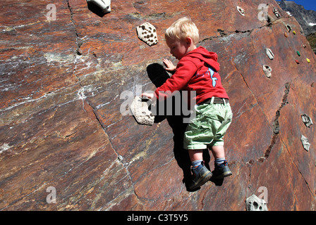 A young boy having his first taste of rock climbing on an outdoor wall in Switzerland. Stock Photo