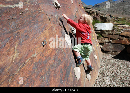 A young boy having his first taste of rock climbing on an outdoor wall in Switzerland. Stock Photo