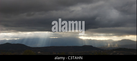 Sun beams bursting through very dark threatening clouds Stock Photo