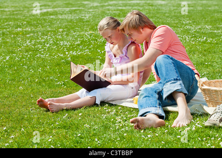 Teenager brother and sister having a picnic in the park in a bright sunny day Stock Photo