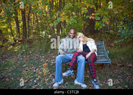 Couple sitting on park bench in autumn Stock Photo