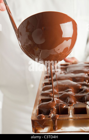 Baker pouring chocolate in mold Stock Photo