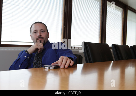Young businessman in conference room with smartphone, May 6, 2011, © Katharine Andriotis Stock Photo