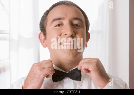 Hispanic man tying bow tie Stock Photo
