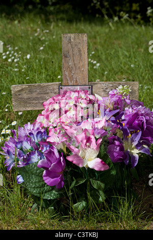 Floral tribute on simple wooden cross maker of a grave in a Norwich cemetery, Norfolk, England, UK. Stock Photo