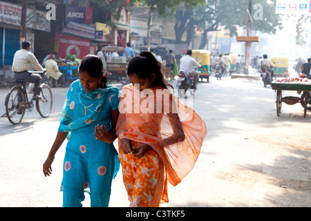 Indian women with sari walking in the streets of Varanasi, Uttar Pradesh, India, Asia. Female friends and city road with traffic Stock Photo