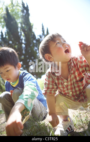 Two Boys Crouching in Grass Stock Photo