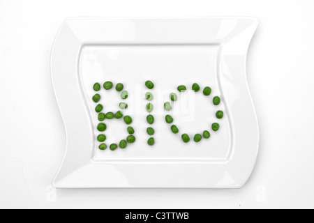 peas on a white plate which are writing bio Stock Photo