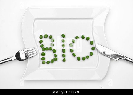 peas on a white plate which are writing bio Stock Photo
