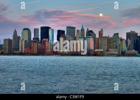 Full moon rising over lower Manhattan at sunset seen from across the Hudson River in New Jersey Stock Photo
