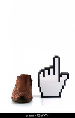 Brown male shoe beside pixeled black and white cursor hand sign on white background Stock Photo