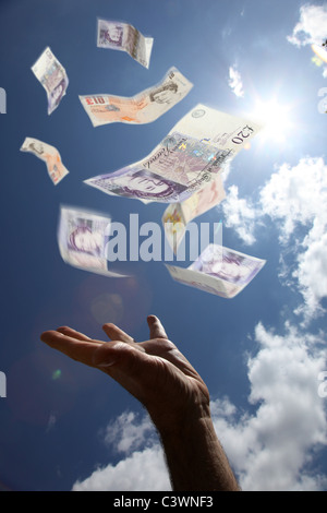 £10 and £20 notes falling from the sky, a male hand reaching up to catch the money. Stock Photo