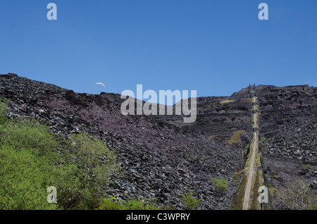 Paraglider appearing above the horizon, near an A5 incline at Dinorwig slate mine, Snowdonia, North Wales, UK Stock Photo