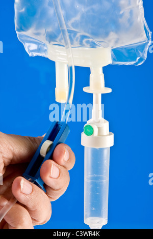 Nurse's hands regulation an IV drip in hospital Stock Photo