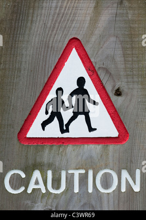 Triangular Pedestrian crossing caution sign carved into wood Stock Photo