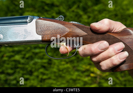 mans hand holding double barrel shotgun with finger on the trigger.landscape format.copy space. Stock Photo
