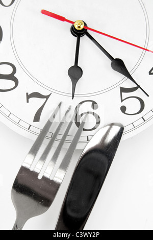 fork and wall clock with white background, concept of dinner time Stock Photo