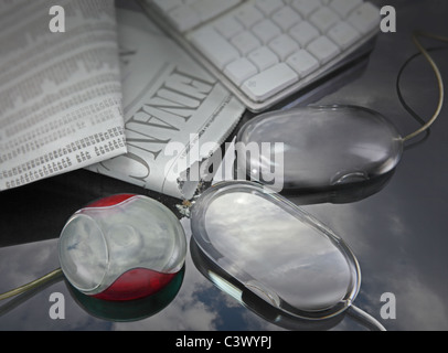 three computer mice ingesting newspaper information to convert to digital. Stock Photo