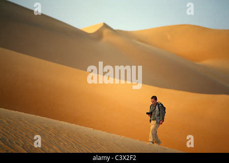 Algeria, Djanet, Sahara Desert, Photographer Frans Lemmens walking on sand dune. Stock Photo