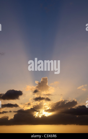 Sunbeams bursting through cloud at sunset. Stock Photo
