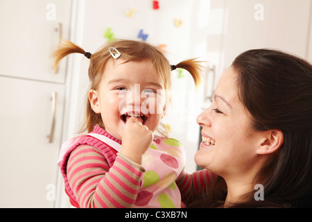 Mother and daughter laughing in kitchen Stock Photo