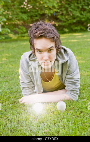 Young man lying on grass with two lightbulbs Stock Photo
