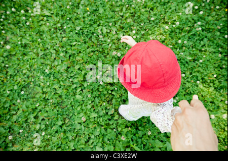 Man holding hand of baby daughter taking her first steps Stock Photo