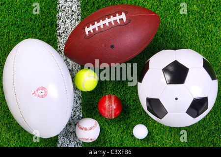 Photo of various sports balls on a grass next to the white line, shot from above.
