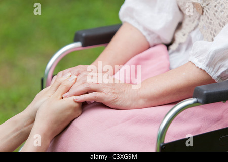 Healthcare worker and senior woman holding hands, Tokyo Prefecture, Honshu, Japan Stock Photo