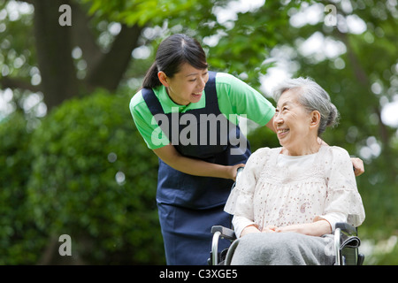 Healthcare worker pushing senior woman in wheelchair, Tokyo Prefecture, Honshu, Japan Stock Photo