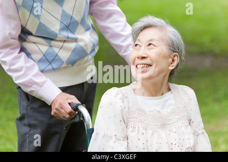 Senior man pushing senior woman on wheelchair, Tokyo Prefecture, Honshu, Japan Stock Photo