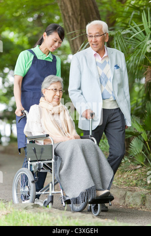 Healthcare worker pushing senior woman in wheelchair, Tokyo Prefecture, Honshu, Japan Stock Photo