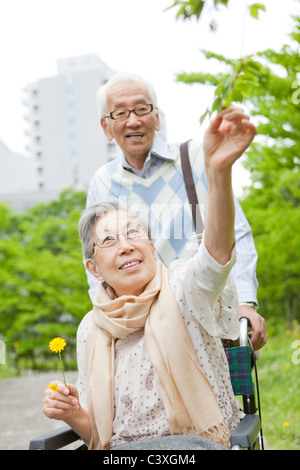 Senior man pushing senior woman on wheelchair, Kanagawa Prefecture, Honshu, Japan Stock Photo