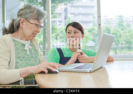 Senior woman and healthcare worker using laptop, Kanagawa Prefecture, Honshu, Japan Stock Photo