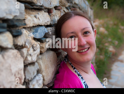 Young lady posing by an old stone wall Stock Photo