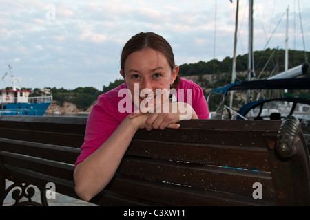 A young lady  posing on a bench at the harbor of Patitiri, Alonissos Stock Photo