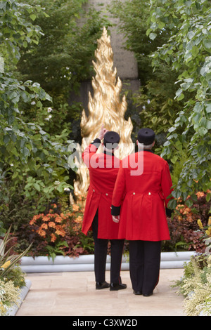 Two Chelsea pensioners look at a £70,000 cypress tree sculpture covered in 23.5 carat gold at the 2011 RHS Chelsea Flower Show Stock Photo