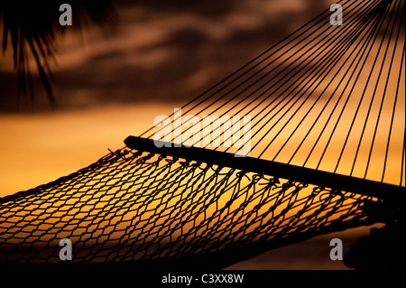 silouhette of hammock on beach overlooking ocean at sunset Stock Photo